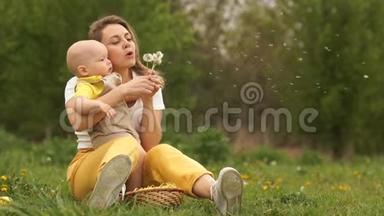 年轻的<strong>妈妈</strong>和宝宝正在草地上坐在公园里吹蒲公英。 <strong>妈妈</strong>`天，<strong>妈妈</strong>和宝贝。 副本